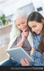 cute little girl using tablet pc with grandma at home