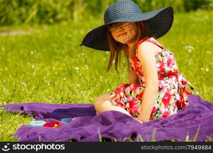Cute little girl wearing big summer hat pretending to be woman lady. Child imitate mother playing in park, outdoors
