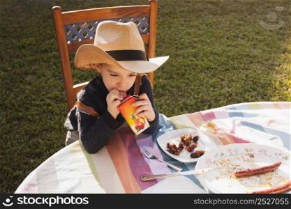 cute little girl wearing hat drinking juice