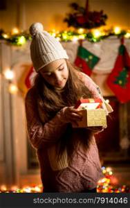 Cute little girl wearing sweater looking in gift box at Christmas eve