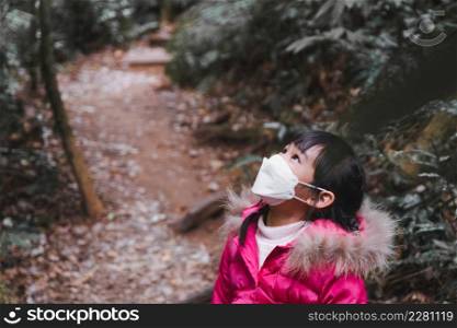 Cute little girl with backpacks hiking in nature with family. child looking up on tree. Preschoolers in winter clothes explore the forest, play and learn in nature.