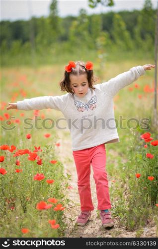 Cute little girl with four years old having fun in a poppy field