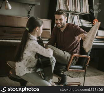 Cute little girl with guitar teacher in the room at home