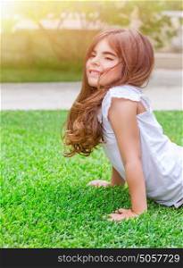Cute little girl with pleasure doing push-ups outdoors, exercising on fresh green spring field in sunny day, health lifestyle, active childhood concept