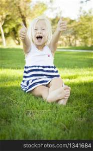 Cute Little Girl with Thumbs Up in the Grass Outside.