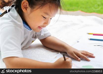 cute little girl writes to writing-books. The decision of lessons. girl lay down drawing the picture