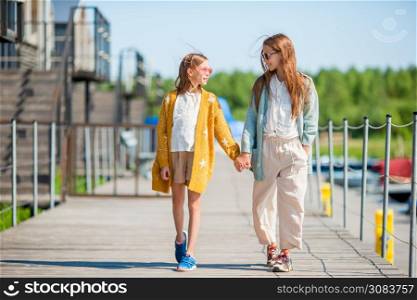 Cute little girls in the port walking together. Adorable little girls in port on vacation
