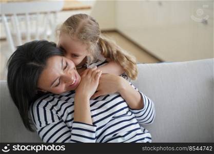 Cute little kid hugs mom. Affectionate family has happy moments together. Young handsome european mother and daughter. Woman and girl together at home. Motherhood and togetherness concept.. Cute little kid hugs handsome mom. Affectionate happy family has moments together at home.