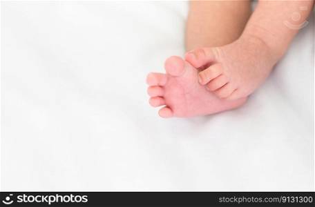 Cute little newborn baby feet on white bedding at home, soft focus background with copy space.