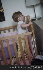 cute  little one year old baby playing with toys in bed while making first steps and learnig to walk