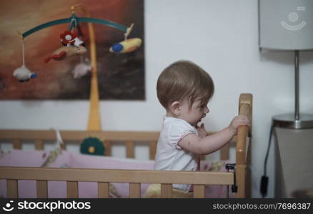 cute  little one year old baby playing with toys in bed while making first steps and learnig to walk