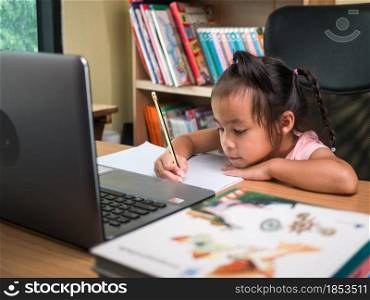 Cute little schoolgirl studying homework math during her online lesson at home, social distancing during the coronavirus outbreak. Concept of online education or home schooler.