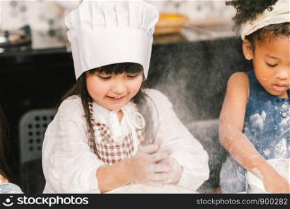 Cute mixed race and African American kid girls baking or cooking together in home kitchen. Education activity, youth culture, or smart young children concept