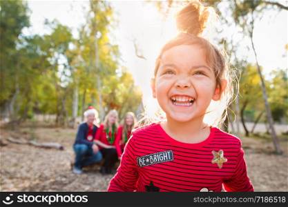 Cute Mixed Race Baby Girl Christmas Portrait With Family Behind Outdoors.