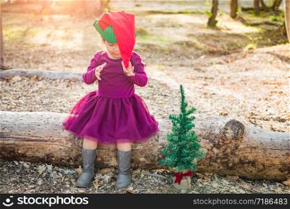 Cute Mixed Race Young Baby Girl Having Fun With Christmas Hat and Tree Outdoors.