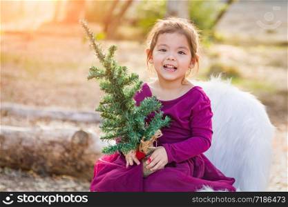 Cute Mixed Race Young Baby Girl Holding Small Christmas Tree Outdoors.