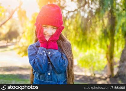 Cute Mixed Race Young Girl Wearing Red Knit Cap and Mittens Outdoors.