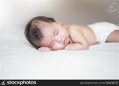 cute newborn baby is sleeping on white bed