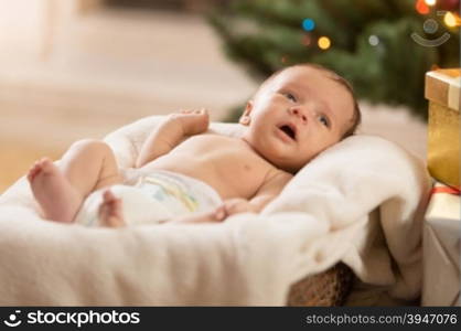 Cute newborn baby lying on beige blanket in wicker basket