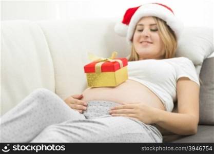 Cute pregnant woman getting ready for Christmas posing with gift box