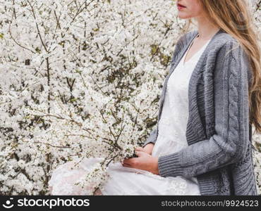 Cute, pretty woman on the background of flowering trees. Concept of rest and relaxation. Cute woman on the background of flowering trees