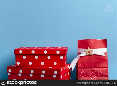 Cute red gift boxes and a red shopping bag with a number on a blue background. Christmas presents context. Xmas gifting concept. Advent calendar frame
