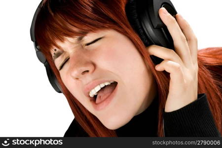 Cute redhead girl enjoying and singing music on her headphones. Studio shot.