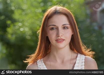 Cute redhead young women front view looking at camera. Backlit by sunset