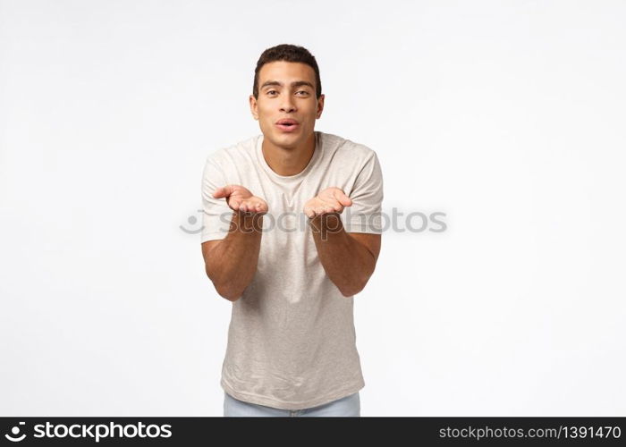 Cute, romantic pationate hispanic man in t-shirt, blowing kisses, fold lips smiling flirty and hold hands neart mouth, send mwah to camera, standing white background express affection or sympathy.. Cute, romantic pationate hispanic man in t-shirt, blowing kisses, fold lips smiling flirty and hold hands neart mouth, send mwah to camera, standing white background express affection or sympathy