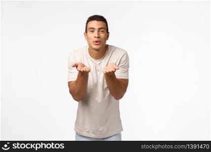 Cute, romantic pationate hispanic man in t-shirt, blowing kisses, fold lips smiling flirty and hold hands neart mouth, send mwah to camera, standing white background express affection or sympathy.. Cute, romantic pationate hispanic man in t-shirt, blowing kisses, fold lips smiling flirty and hold hands neart mouth, send mwah to camera, standing white background express affection or sympathy