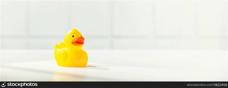 Cute rubber duck on white bathroom countertop with space for text, horizontal composition, banner