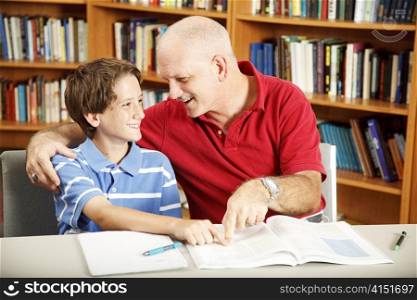 Cute school boy gets help with his homework from Dad.