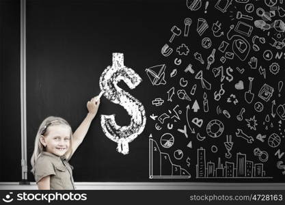 Cute school girl drawing dollar sign on blackboard. Girl at blackboard