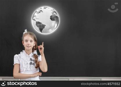 Cute school girl pointing at globe above her head. At geography lesson