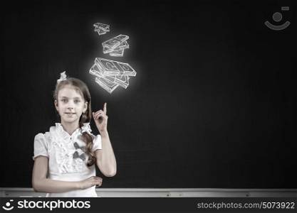 Cute school girl pointing at money drawn on blackboard. Girl at blackboard