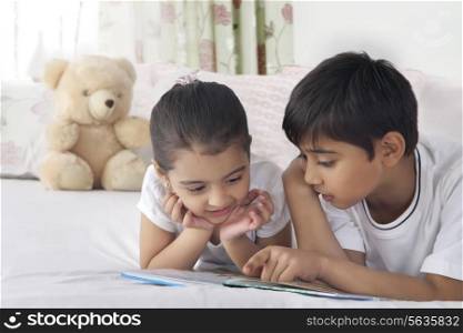 Cute siblings reading book in bed