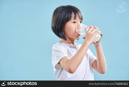 Cute smart asian little girl drinking milk on blue background
