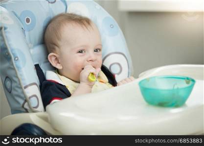 Cute smiling baby boy eating with spoon