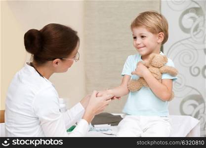 Cute smiling boy at the doctor with his little toy friend, not affraid to visit pediatrician, happy healthy childhood