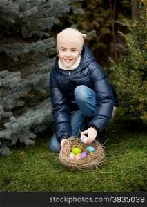 Cute smiling girl collecting Easter eggs at backyard