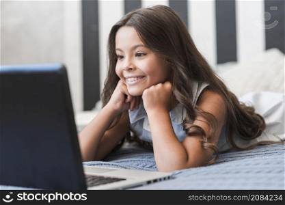 cute smiling girl lying bed watching video laptop
