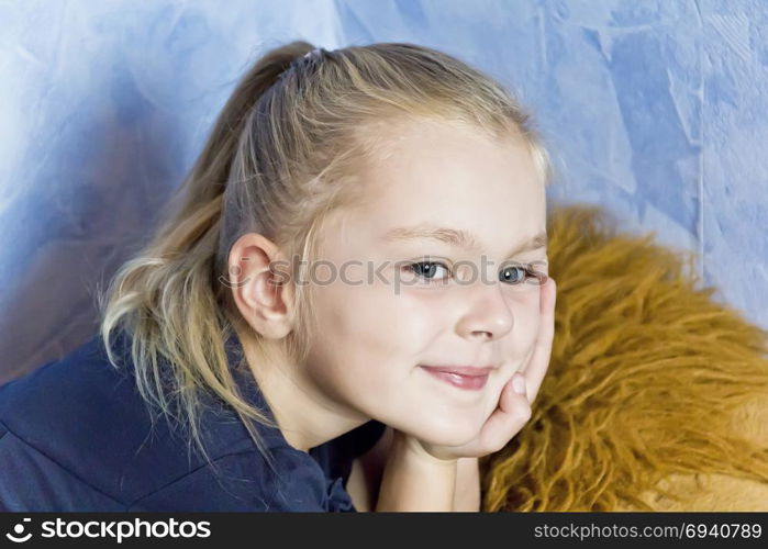 Cute smiling girl with blond hair on blue background