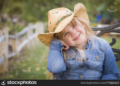 Cute Smiling Young Girl Wearing Cowboy Hat Posing for a Portrait Outside.