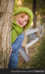 Cute Smiling Young Girl Wearing Green Scarf and Hat Posing for a Portrait Outside.