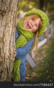 Cute Smiling Young Girl Wearing Green Scarf and Hat Posing for a Portrait Outside.
