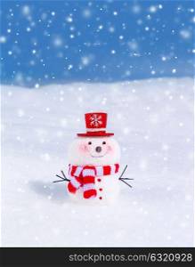 Cute snowman outdoors in snowy weather, traditional winter decoration, little smiling snowman wearing red hat and scarf, Christmas greeting card