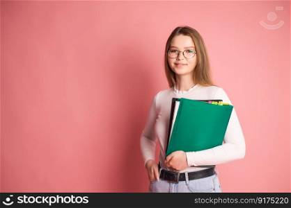 Cute student girl with glasses holds folders on pink background.. Cute student girl with glasses holds folders on pink background