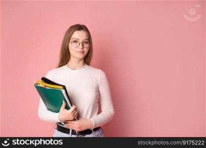 Cute student girl with glasses holds folders on pink background.. Cute student girl with glasses holds folders on pink background