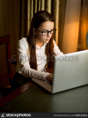 Cute teenage girl in white shirt typing message on computer