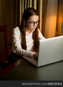 Cute teenage girl in white shirt typing message on computer